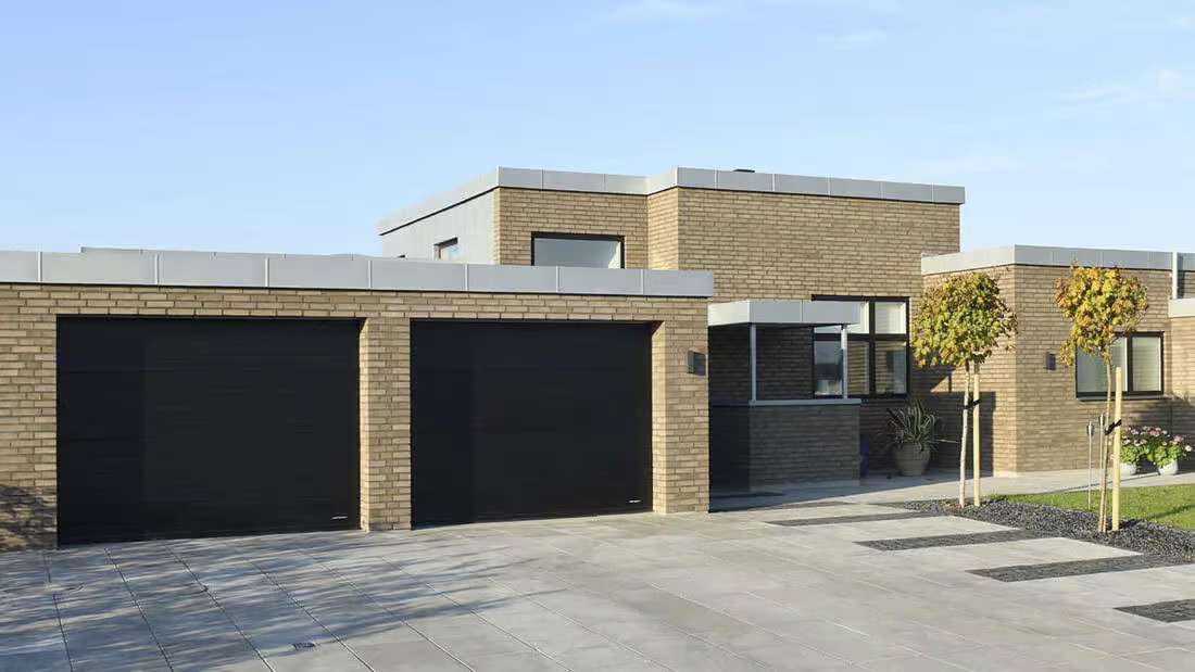 Modern garageport från Lindab Doorline monterad på villa, med stilren design och integrerad gångdörr.