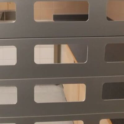 Detalj av aluminiumjalusi med stora urstansade öppningar för genomsikt.