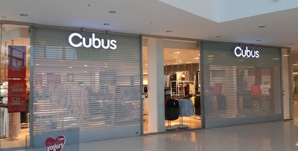 Aluminiumjalusi med genomsikt monterad vid butiksentré i galleria.